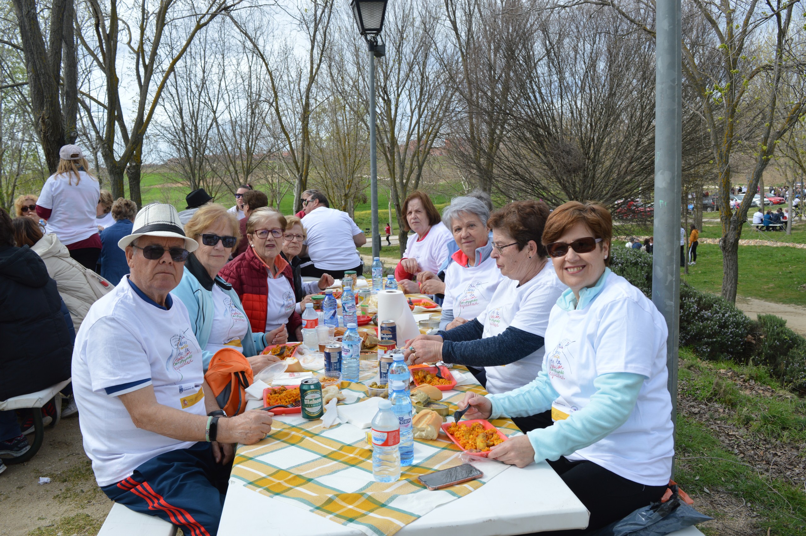 Vecinos y vecinas comen paella en el Prado de la Casa